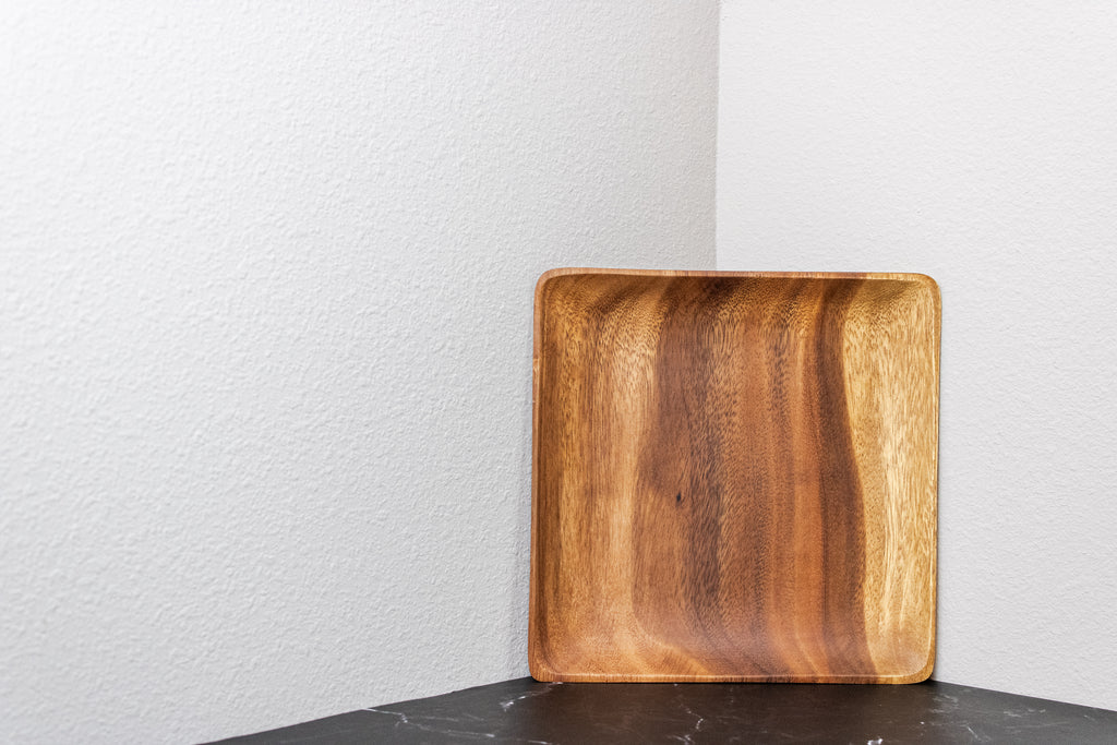 Wooden tray on a black surface with a white wall background